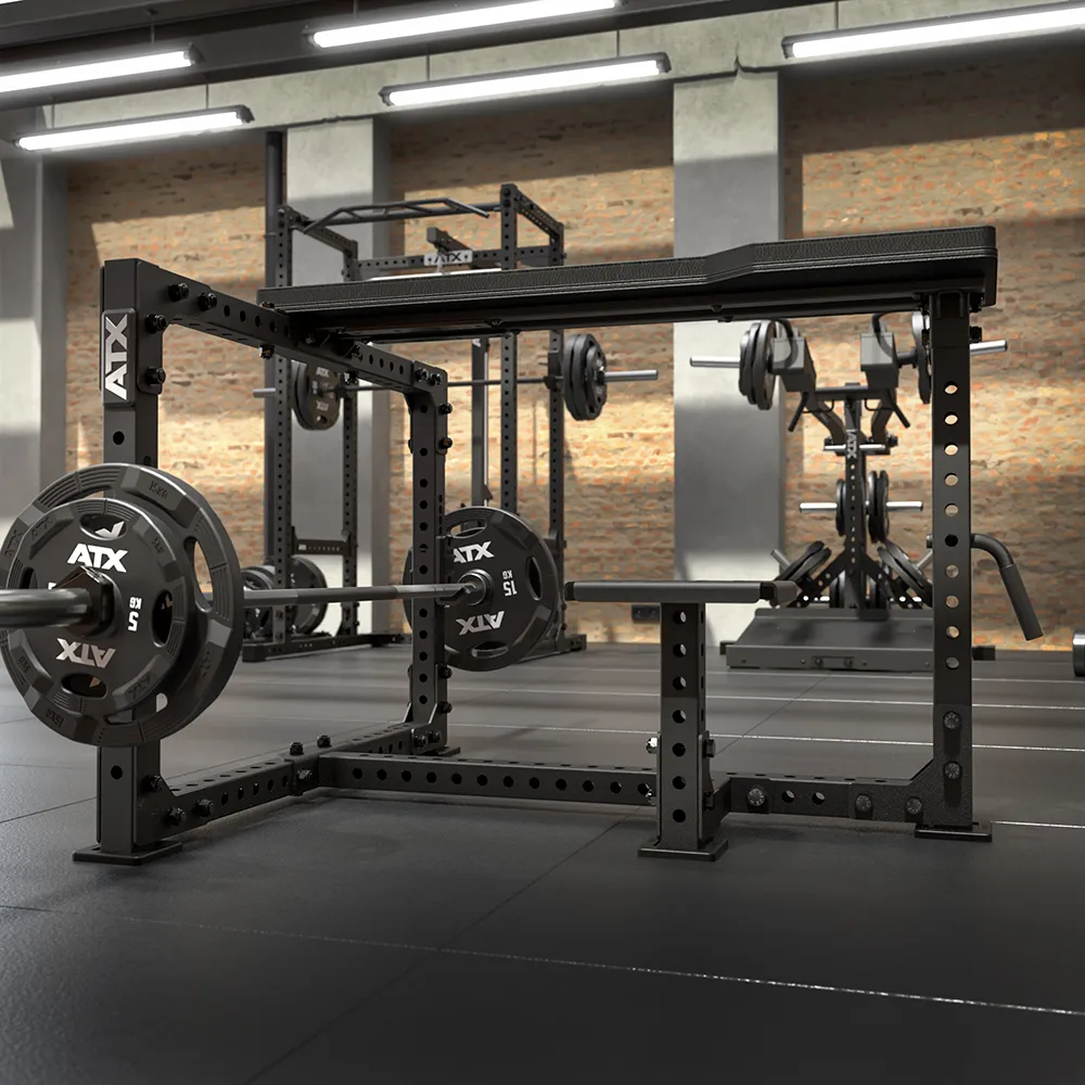 A gym featuring an ATX® Seal Row Bench, loaded barbells, and diverse weightlifting gear. The space includes rubber flooring, brick walls, and overhead lighting.