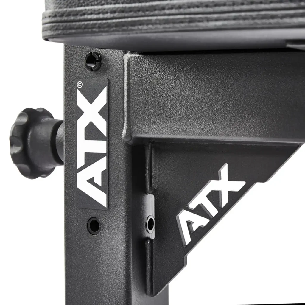 Close-up of a black metal workout bench attachment with ATX® in white lettering on the side. The ATX® Flat Workout Bench Attachment features padded elements and a textured adjustment knob for customization.