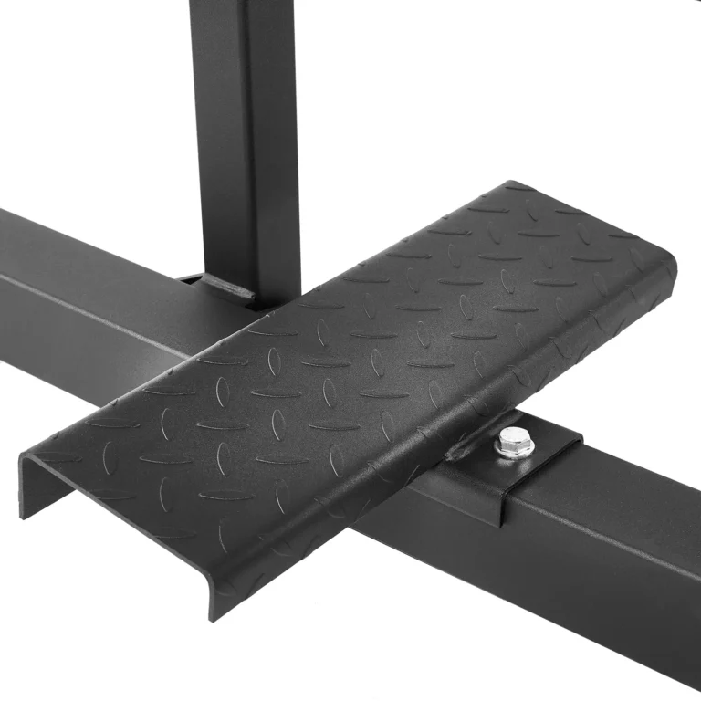 Close-up of a metal foot pedal with a textured diamond plate surface on the ATX Seated Calf Raise Machine's black metal frame. A bolt secures the pedal, showcasing industrial design and construction.