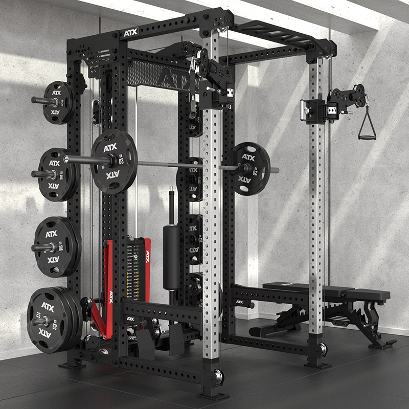 The ATX® Power Cage with Cables gym station includes barbells, weight plates, a bench, and multiple exercise accessories, all arranged in a modern fitness space with concrete walls.