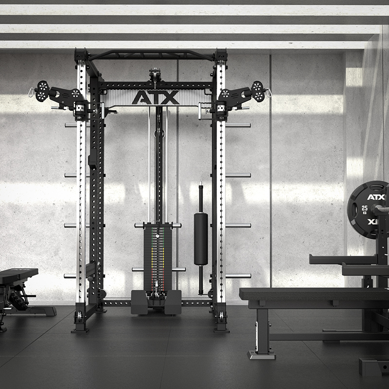 A modern, empty gym features the ATX® Power Cage with Cables, benches, and weight plates set against a concrete wall in a well-lit, minimalistic space.