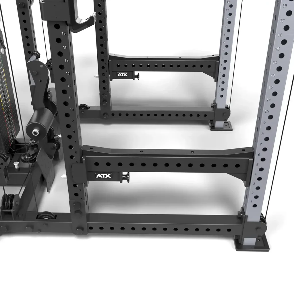 Close-up of an ATX® Power Cage with Cables, black and gray, featuring adjustable holes and ATX branding. Designed for strength training, this sturdy metal rack is set against a white background.