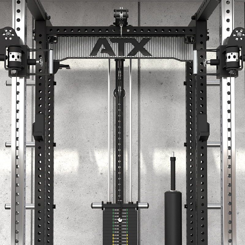 A close-up of the ATX® Power Cage with Cables features metal bars, weight stacks, and adjustable pulleys in front of a concrete wall. The letters AIX appear on a metal mesh near the top.