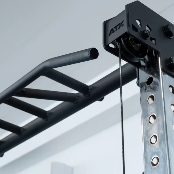 Close-up of the ATX® Power Cage with Cables, featuring a sleek black and silver design with an attached pull-up bar. The metal frame includes multiple adjustment holes, prominently displaying the ATX branding. A white ceiling completes the background.