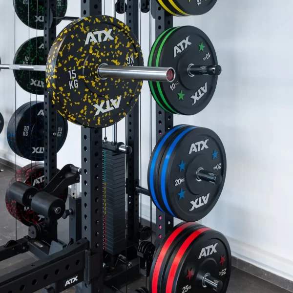 A colorful weight rack featuring speckled plates from 15 kg to 25 kg complements the ATX® Power Cage with Cables, creating an essential component of the fitness centers strength training setup.