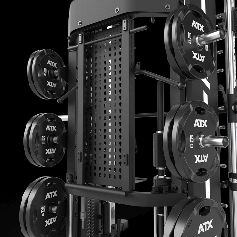 Close-up of the ATX® Monster 2.0 All In One Trainer loaded with ATX weight plates in 10 kg, 15 kg, and 25 kg sizes, arranged on storage pegs against a dark background.