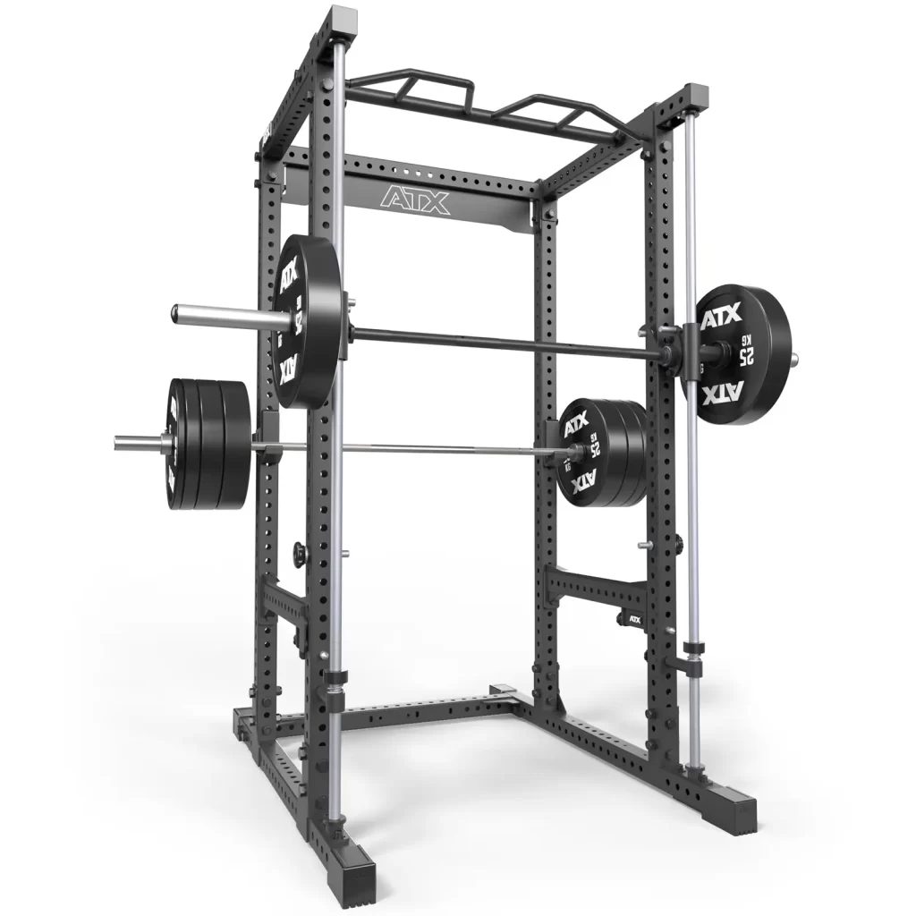 The ATX® Power Rack with Smith Machine is a sturdy gray rack, featuring adjustable safety bars, a top pull-up bar, and multiple holes for adjustments. It supports a barbell loaded with weight plates on each side.