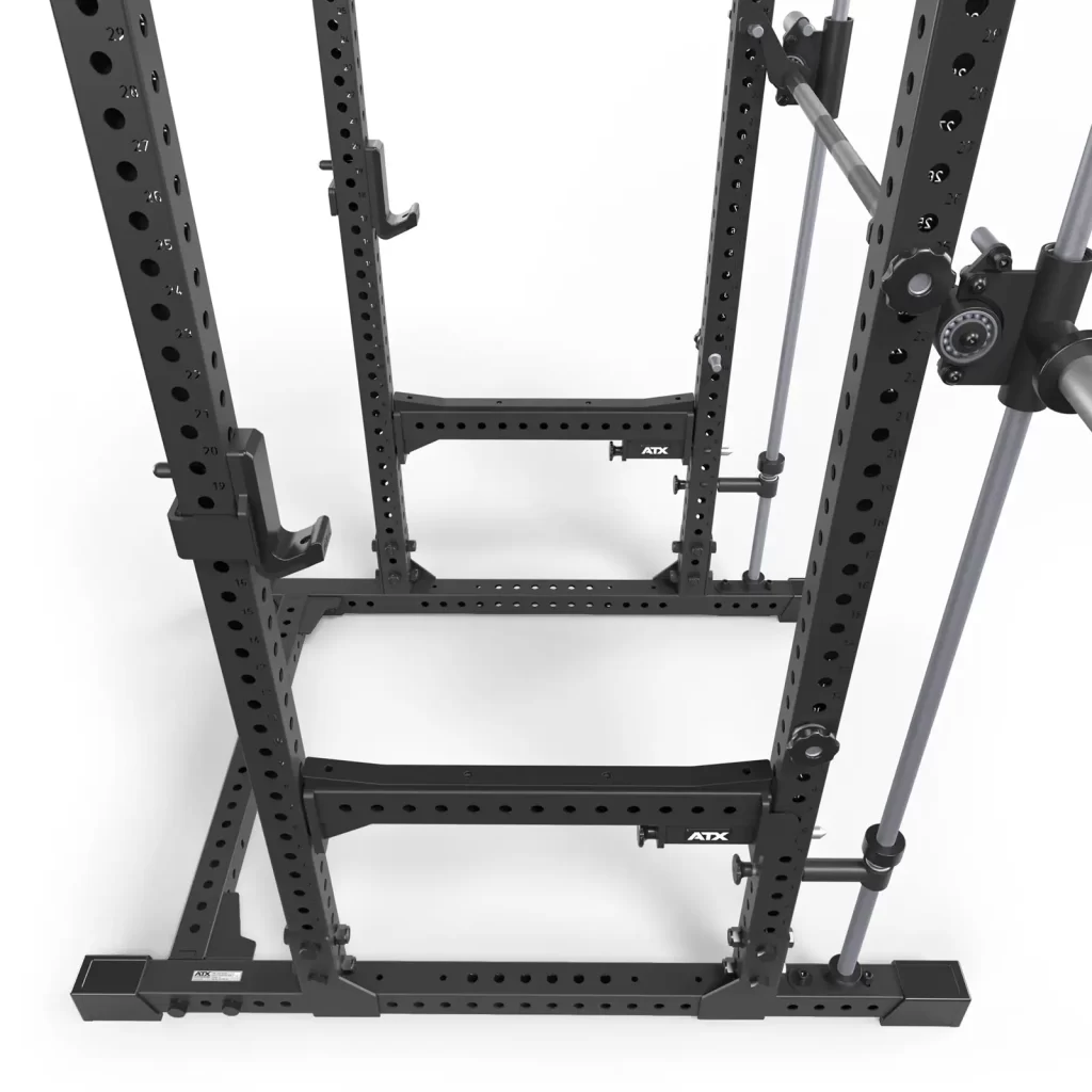 The ATX® Power Rack with Smith Machine is a black power rack, equipped with multiple adjustment holes and attachments for weightlifting, featuring barbell storage supports and safety bars, all on a white background.