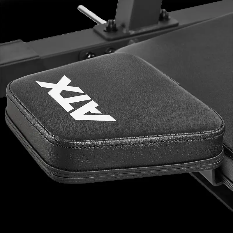 Close-up of a black padded armrest with "ATX" in white letters, attached to the ATX® Vertical Leg Press gym equipment, set against a dark background.
