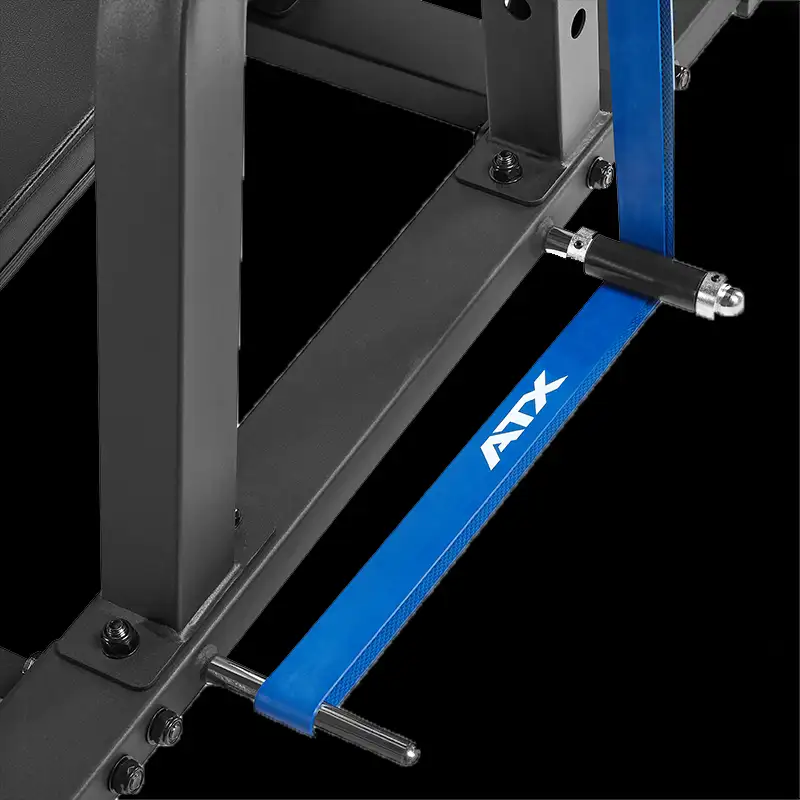 Close-up of an ATX® Vertical Leg Press frame with a blue ATX resistance band attached to two metal pegs at the base. The black background highlights the equipment, making it ideal for vertical leg press training.