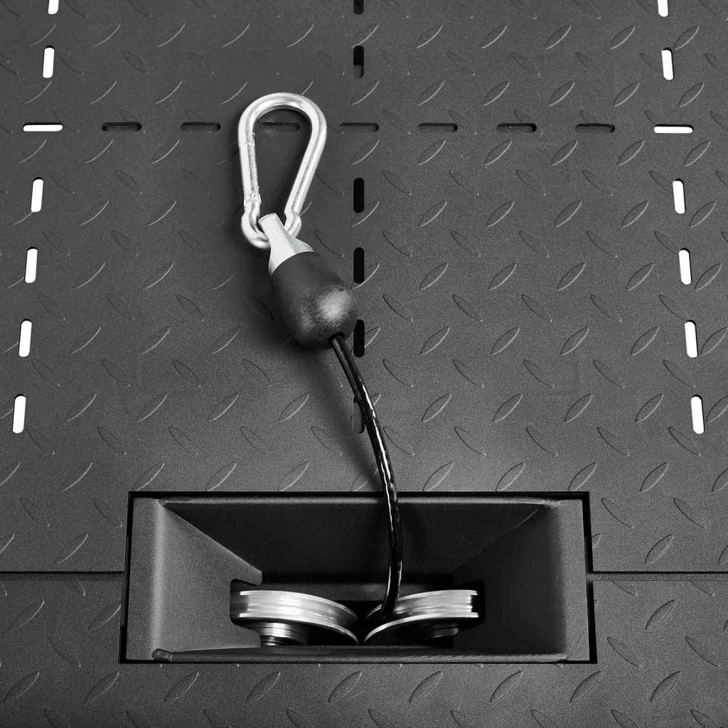 A close-up of a metal carabiner in the ATX-BSM-760 Belt Squat Machine, attached to a cable running through its pulley system, resting on a diamond-patterned textured surface.