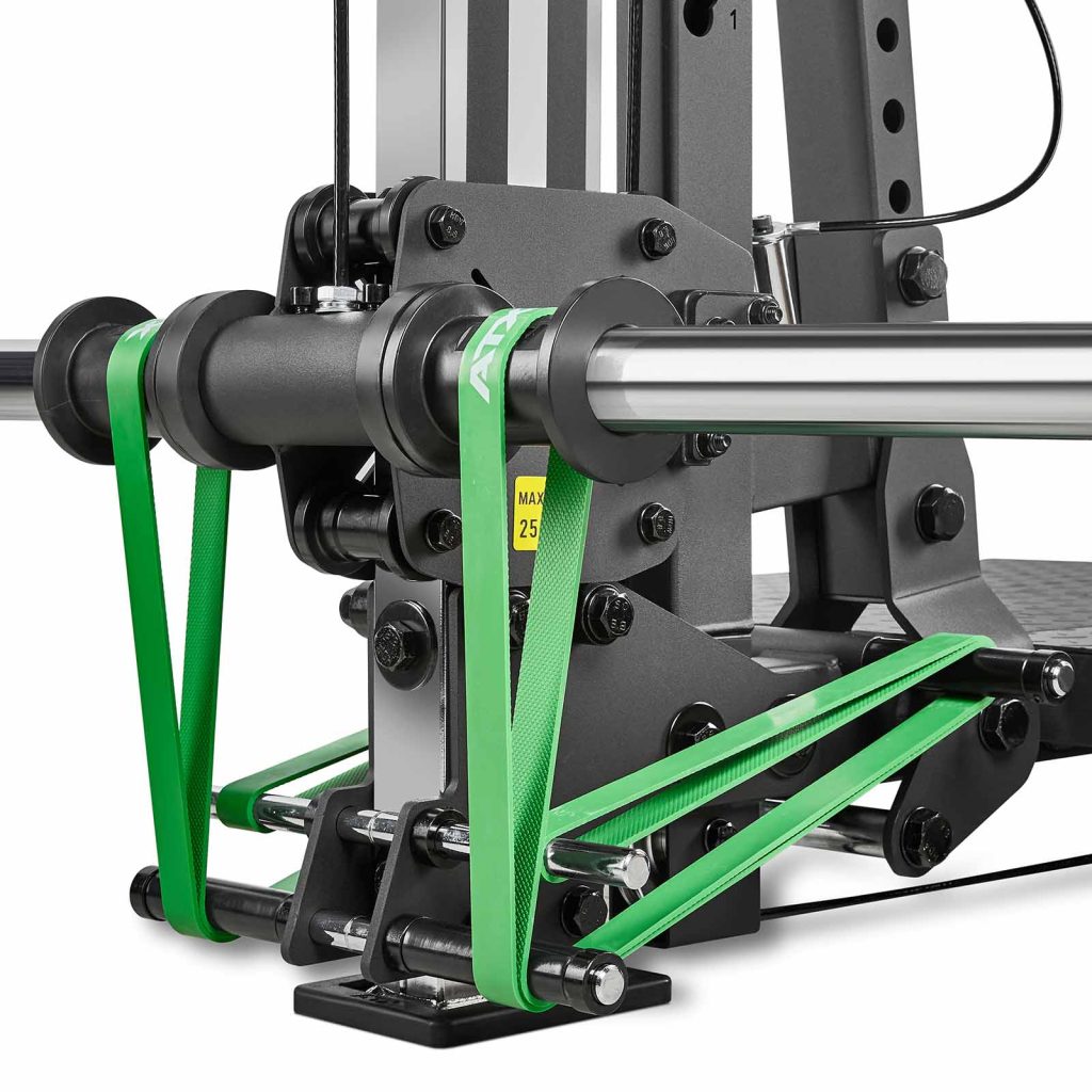 Close-up of the ATX-BSM-760 Belt Squat Machine featuring green resistance bands attached to a metal bar. The sleek black and silver design shows visible bolts, metal plates, and a partially visible yellow caution label for enhanced safety. The bands are stretched taut.