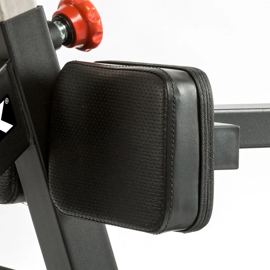 Close-up of the ATX Torso Trainer's black padded leg support with a red adjustment knob, shown against a white background.