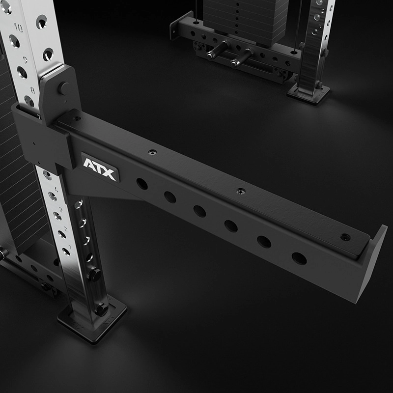 Close-up of a black and silver adjustable spotter arm attached to an ATX Half Rack with Cable Crossover, built for weightlifting safety with multiple adjustment holes and a sturdy, angular design.