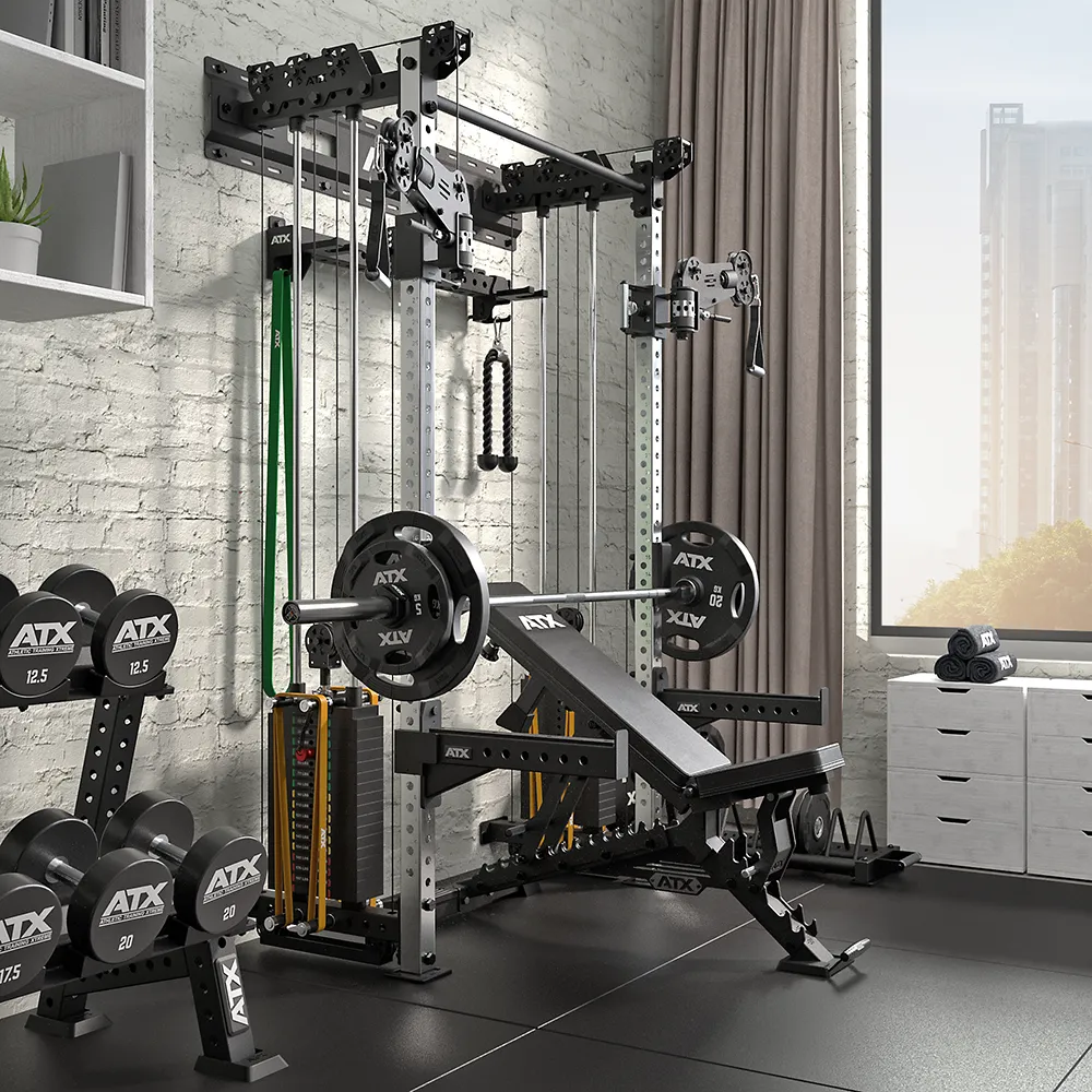 A modern home gym features a weight bench, barbells, dumbbells, resistance bands, and the ATX Half Rack with Cable Crossover by a large window with city views. The space has gray walls and is filled with soft natural light.