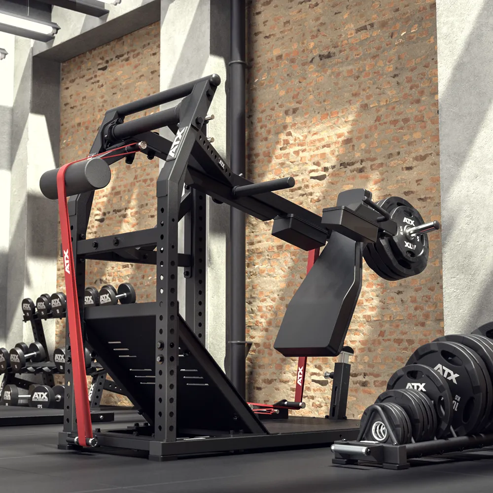 A gym room with exposed brick walls features a black ATX® Pendulum Squat Machine loaded with weights, red resistance bands, and various dumbbells and weight plates stacked nearby.
