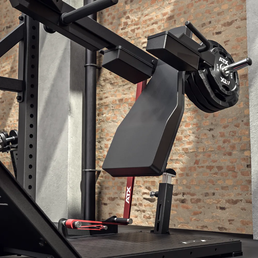 The ATX® Pendulum Squat Machine, featuring padded back support and attached weights for squats or leg exercises, is set against a brick wall in a modern fitness facility.