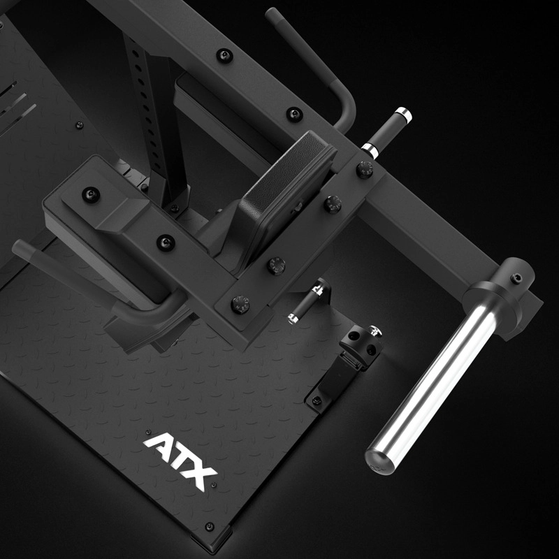 Close-up of the ATX® Pendulum Squat Machine with a textured platform, adjustable padded arm, handles, and chrome bar for strength training, shown against a dark background.