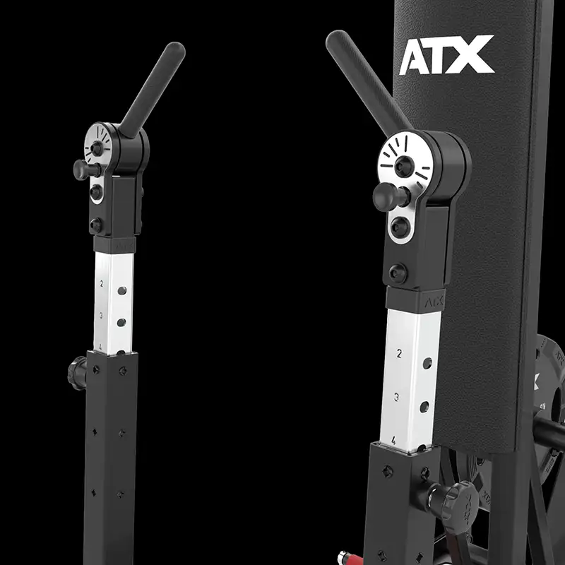 Close-up of two adjustable metal levers with handle grips on the black and silver ATX® Standing Chest Press, featuring ATX branding on the padded section, set against a black background.