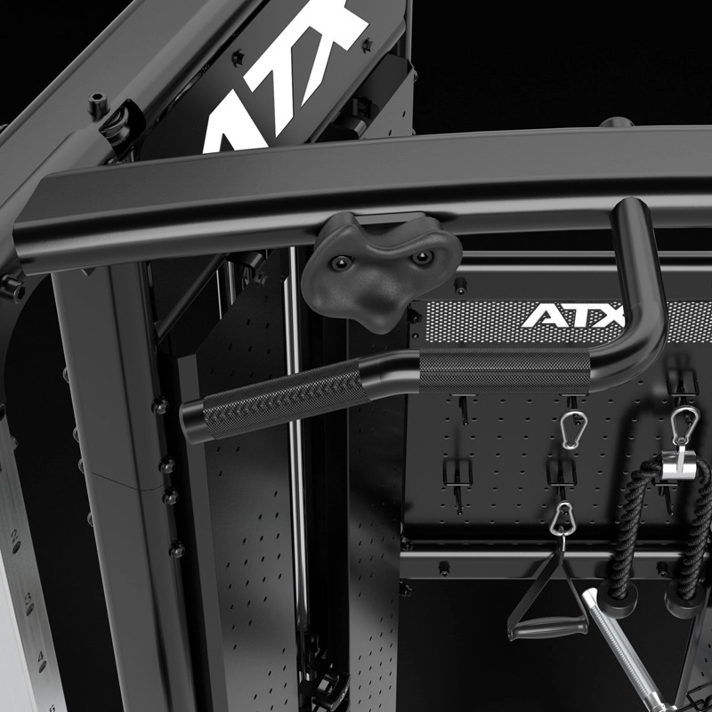 Close-up of a black multi-gym machine with various metal handles, bars, and hooks, including a textured pull-up bar and attachments. The brand name ATX is visible on the machine.