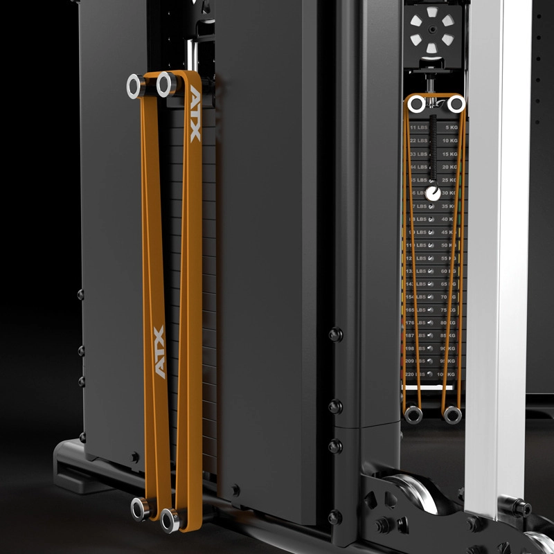 Close-up of a strength training machine showing orange resistance bands labeled ATX attached to a weight stack with visible weight increments and adjustment knobs. The equipment appears sturdy and modern.