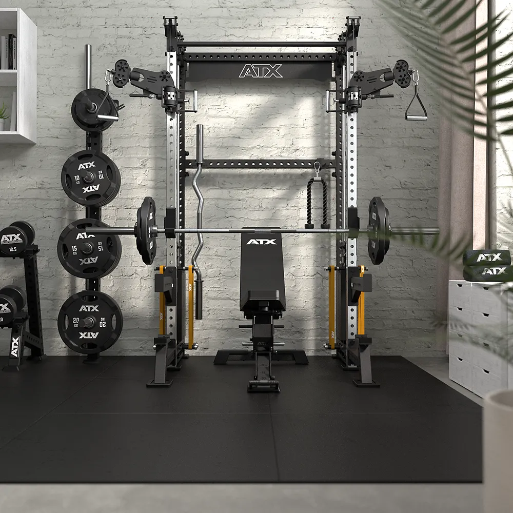 A modern home gym with an ATX power rack, adjustable bench, weight plates, barbells, and various cable attachments, set against a light brick wall with plants and shelves in the background.
