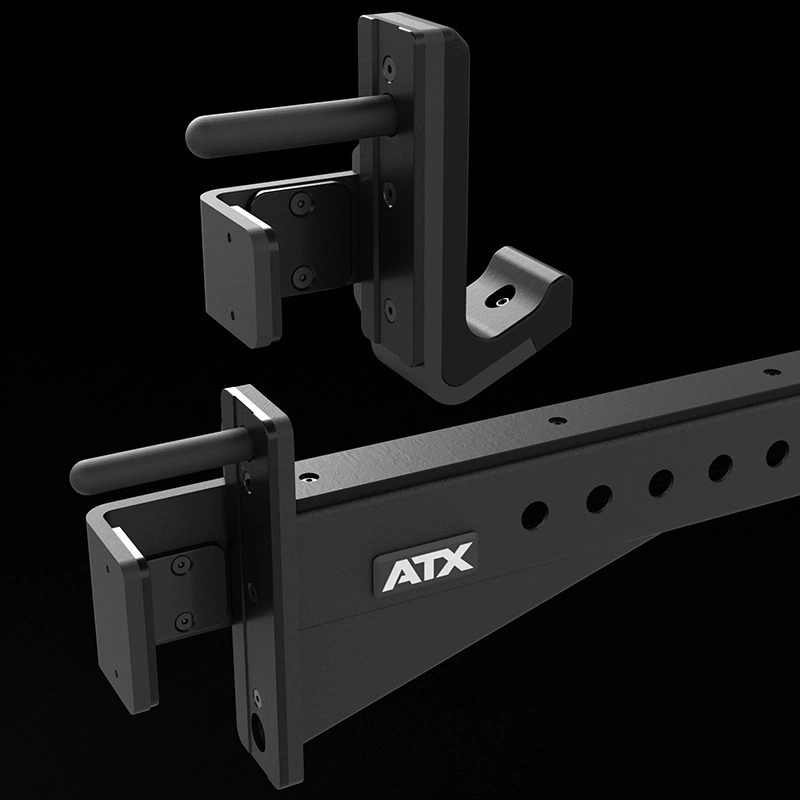 A pair of black metal barbell J-hooks attached to a gym rack with an ATX logo, shown against a black background. The J-hooks have protective pads and multiple holes are visible on the rack.