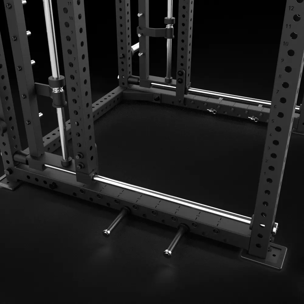 Close-up view of the lower section of a black metal power rack, showing safety bars, numbered holes, and two horizontal pegs for weight storage on a dark gym floor.