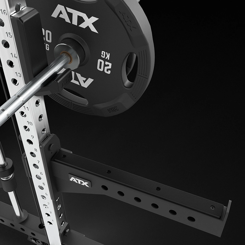 Close-up view of a gym squat rack with a loaded barbell holding a 20 kg weight plate. The equipment is metallic with ATX branding, featuring adjustable holes and a safety bar on a black background.