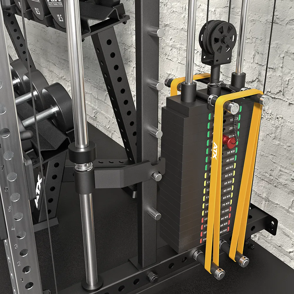Close-up of the ATX® Squat Rack with Cables (Copy), featuring a weight stack, yellow cables, labeled increments, and a textured gray brick wall background. Dumbbells and parts of the metal frame are also visible.