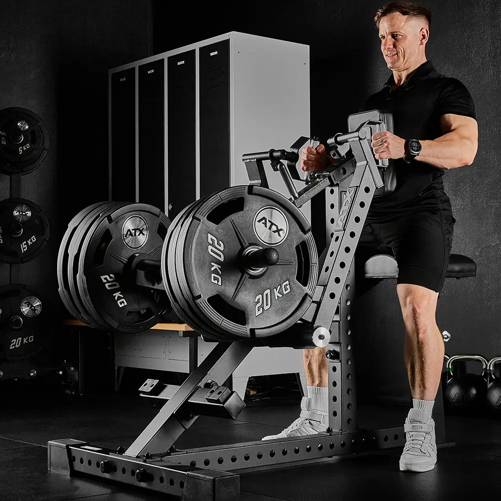 A man in black workout clothes uses the ATX® Chest Supported Row Machine in a gym with black walls and lockers.