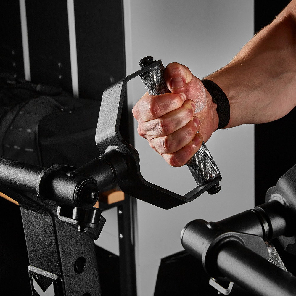 A person grips the handle of the ATX® Chest Supported Row Machine with one hand, displaying detailed muscle tension. The equipment is made of black metal, and the person is wearing a black wristband.