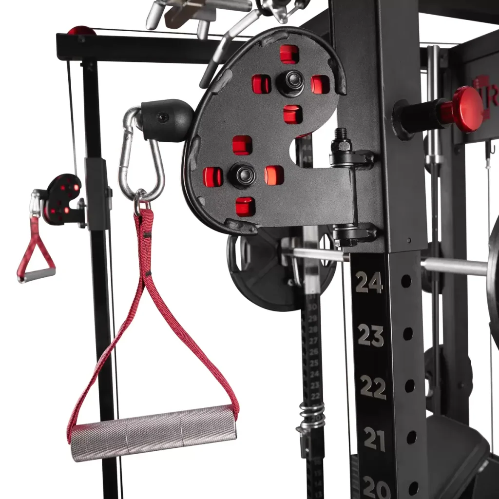 Close-up of a home gym machine’s adjustable pulley system with numbered weight settings, a metal carabiner, and a red and silver exercise handle attached for strength training.