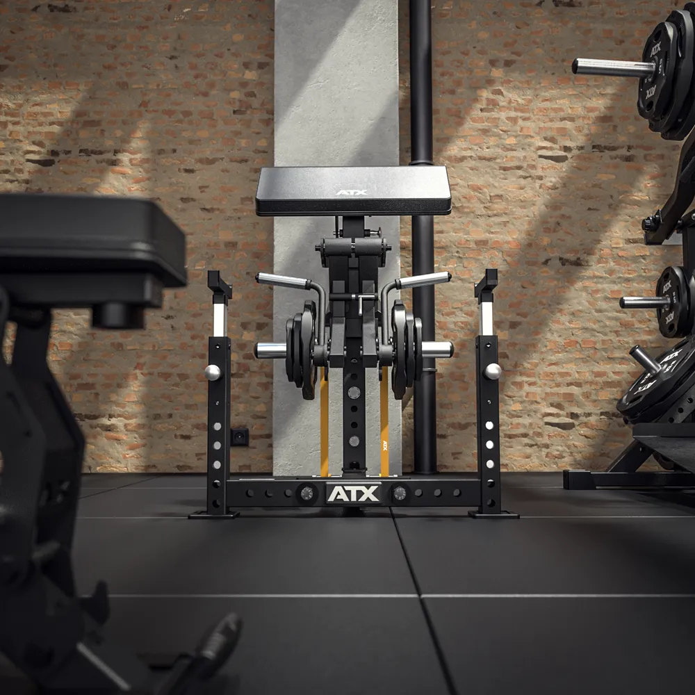 A gym with exposed brick walls features an ATX® Bicep Blaster Preacher Curl Machine, weight plates on both sides, and nearby are other gym benches and equipment.