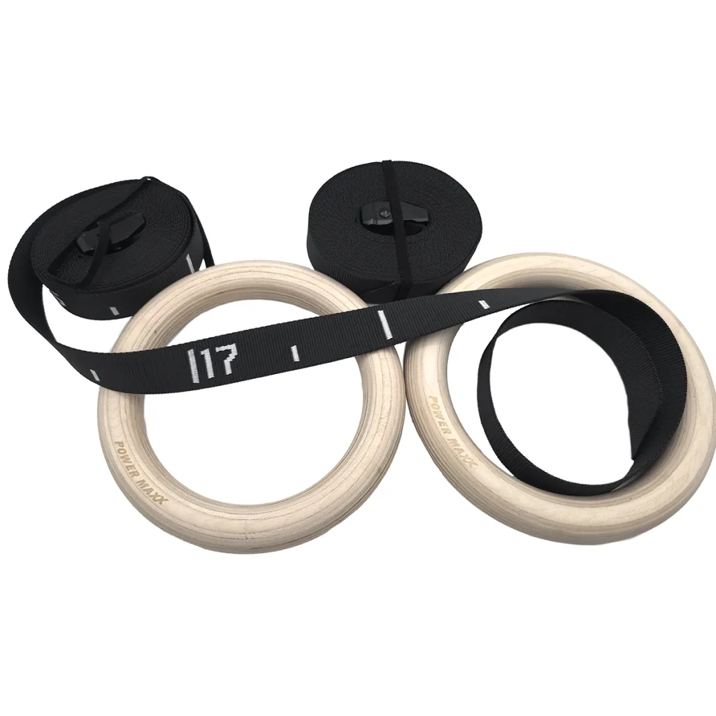 Two wooden gymnastic rings with black adjustable straps coiled beside them, featuring white markings for measurements.