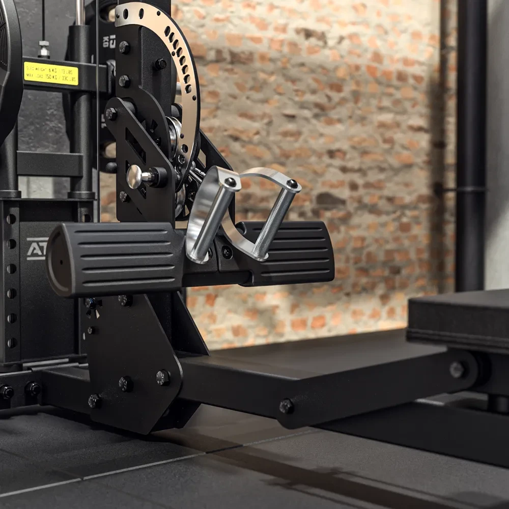 Close-up of a seated row machine in a gym, with black padded footrests, metal handles, and adjustment gears. The background features a brick wall and a bench, creating an industrial fitness setting.