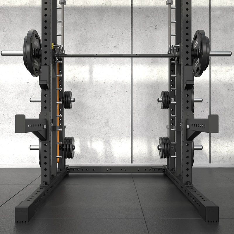 A sleek black power rack with a loaded barbell and weight plates is set up in a gym with a concrete wall background. Alongside the rack, the ATX Commercial Smith Machine complements the professional setup, all standing firmly on a durable rubber floor.