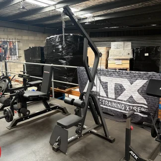 Black ATX lat pulldown machine and leg extension bench in a warehouse gym.